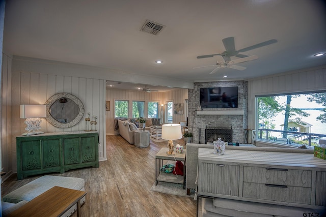 17553 Sleepy Hollow Way, Flint, TX 75762 - living room with a ceiling fan, a stone fireplace, wood finished floors, crown molding, and wooden walls