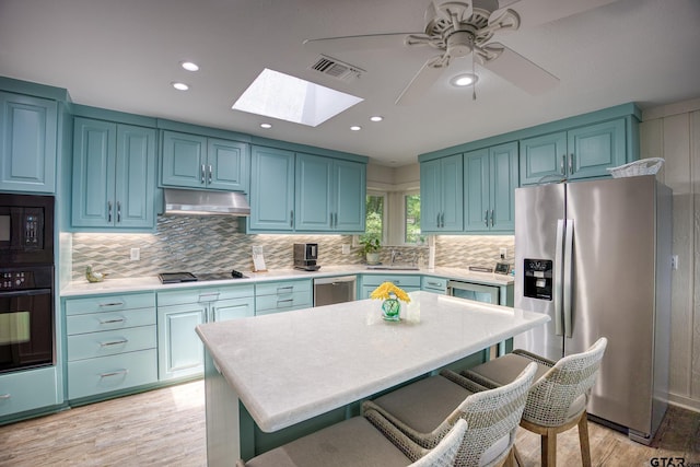 17553 Sleepy Hollow Way, Flint, TX 75762 - kitchen with black appliances, under cabinet range hood, a skylight, light wood-style floors, and light countertops