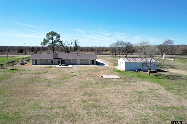 view of yard with a patio, an outdoor structure, and a rural view