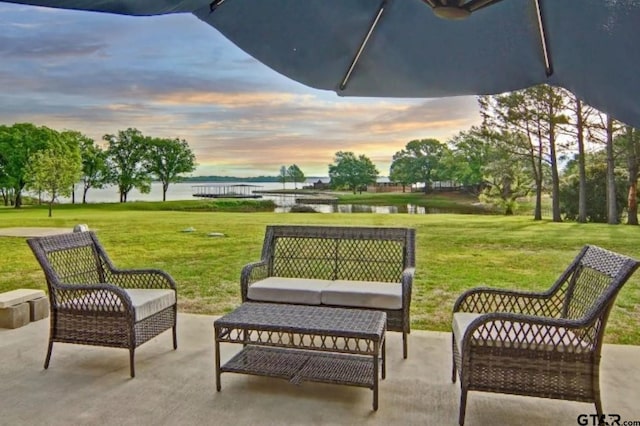 view of home's community featuring a water view, an outdoor living space, a patio, and a lawn