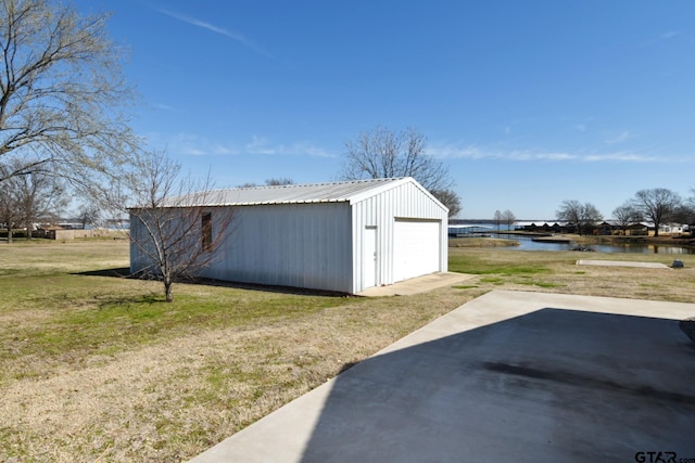 view of outdoor structure featuring a garage, a water view, and a yard