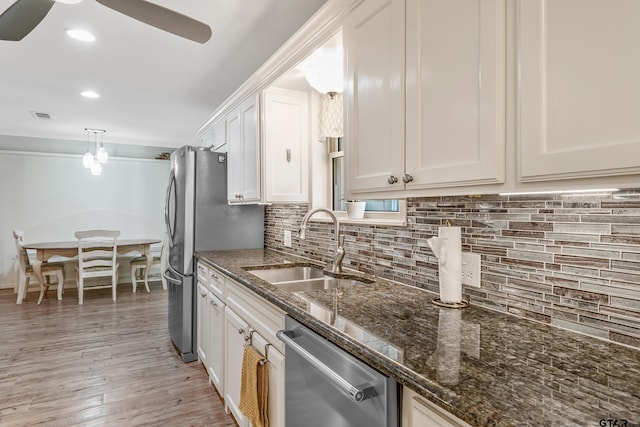 kitchen with appliances with stainless steel finishes, a sink, white cabinets, decorative backsplash, and recessed lighting