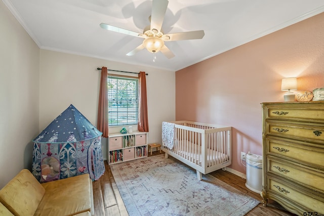 bedroom with wood finished floors, ornamental molding, ceiling fan, and baseboards