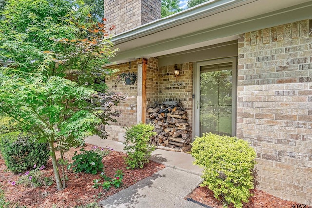 doorway to property with brick siding and a chimney