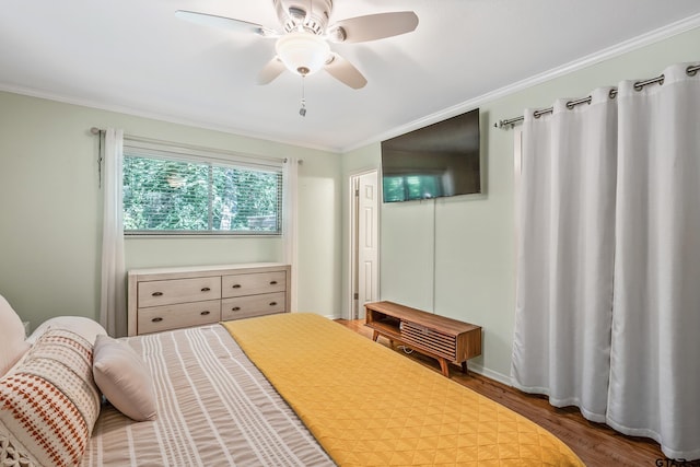 bedroom featuring wood finished floors, ornamental molding, and a ceiling fan