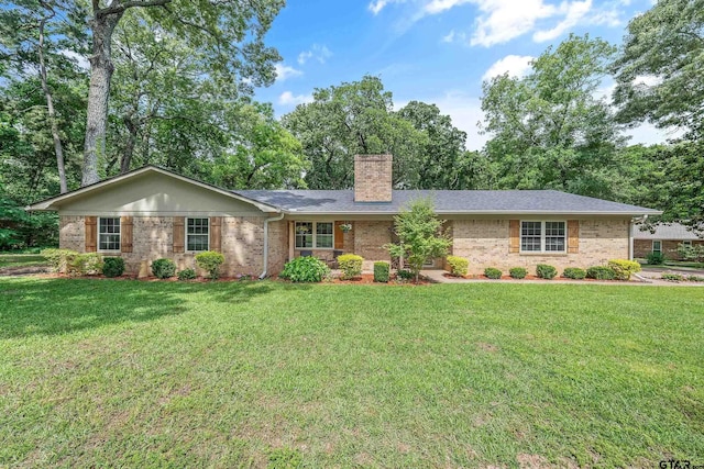 ranch-style home with a chimney, brick siding, and a front yard
