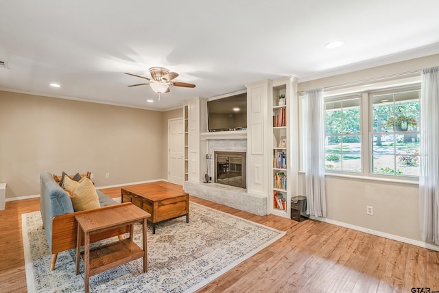 living room featuring baseboards, light wood-type flooring, a brick fireplace, ornamental molding, and recessed lighting