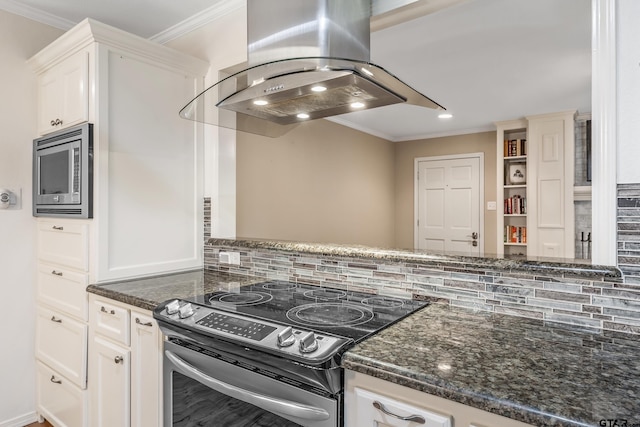 kitchen with appliances with stainless steel finishes, island range hood, ornamental molding, white cabinets, and dark stone counters
