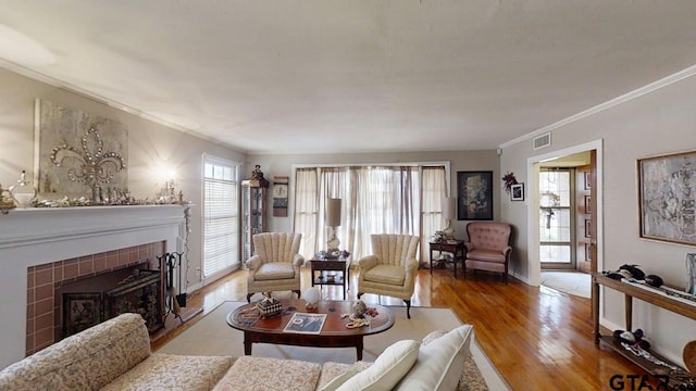 living room featuring crown molding, wood finished floors, and a tiled fireplace