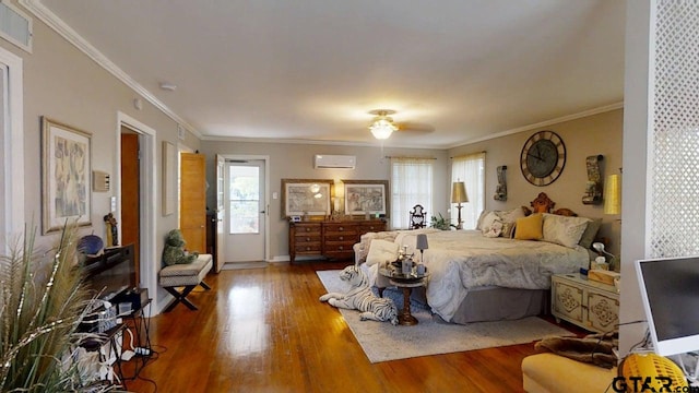 bedroom with a wall unit AC, wood finished floors, ornamental molding, and baseboards