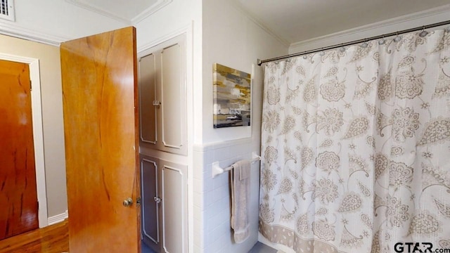 bathroom featuring crown molding, curtained shower, wood finished floors, and wainscoting