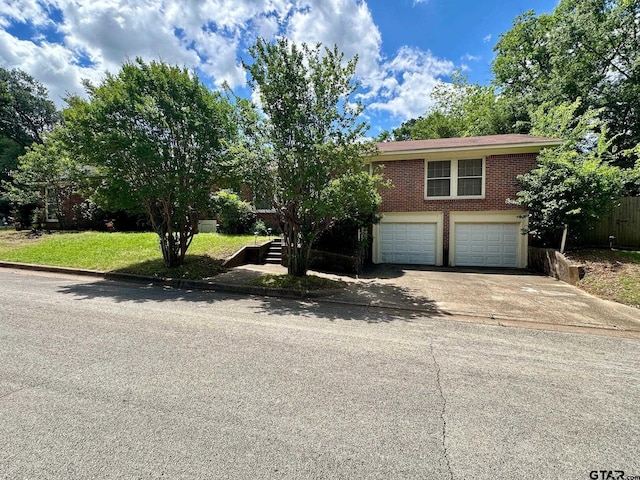 view of front facade with an attached garage, concrete driveway, brick siding, stairway, and fence