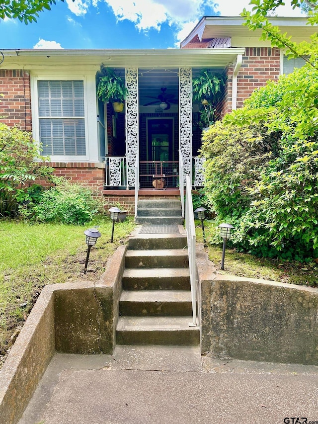 view of exterior entry featuring brick siding and a porch