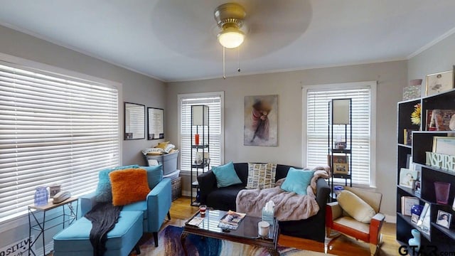living room with a ceiling fan, wood finished floors, ornamental molding, and baseboards