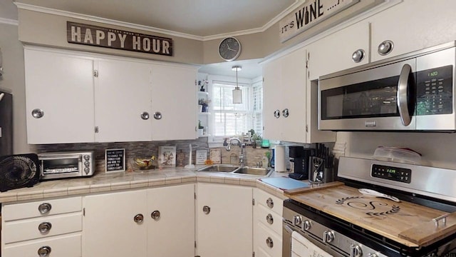 kitchen featuring stainless steel appliances, a sink, white cabinets, and ornamental molding