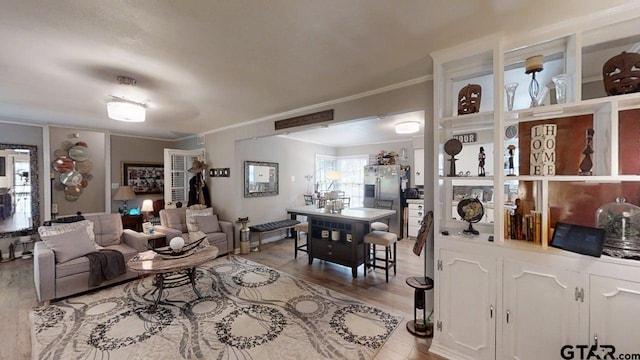 living area featuring crown molding and light wood finished floors