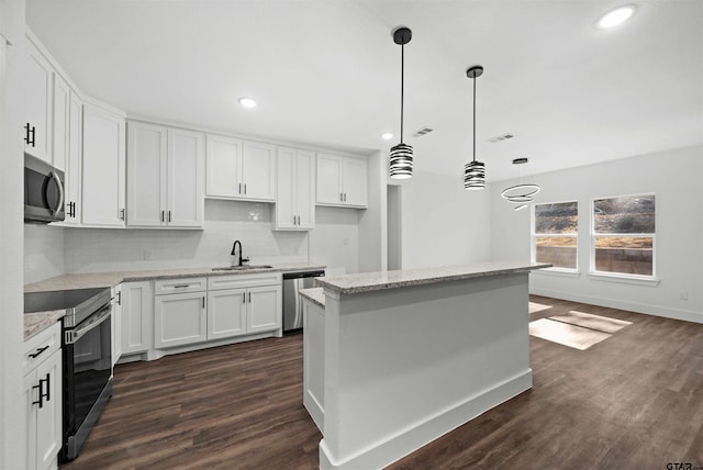 kitchen featuring white cabinets, dark hardwood / wood-style flooring, stainless steel appliances, and hanging light fixtures