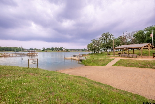 view of dock featuring a gazebo, a water view, and a lawn