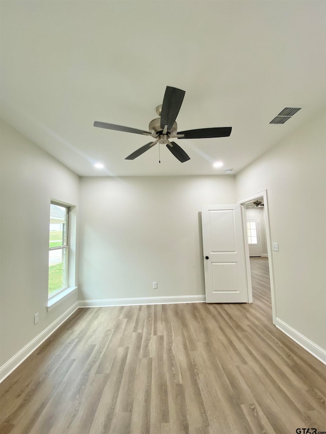 empty room featuring light hardwood / wood-style flooring, ceiling fan, and a healthy amount of sunlight