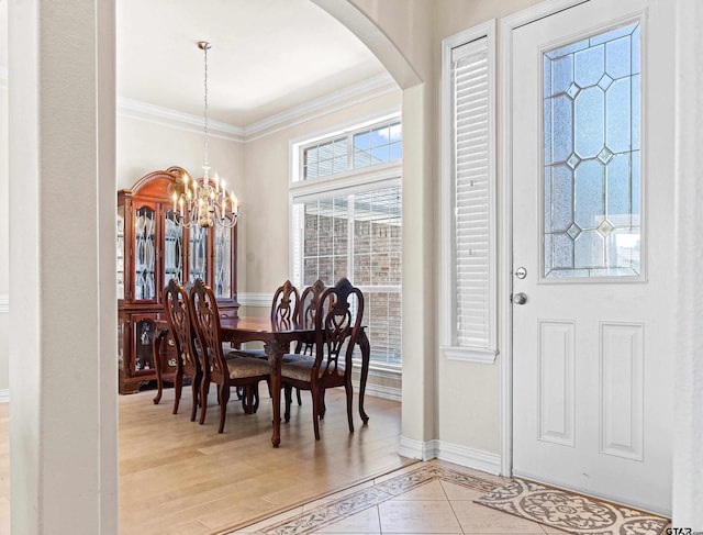 dining area with crown molding, light hardwood / wood-style flooring, and an inviting chandelier