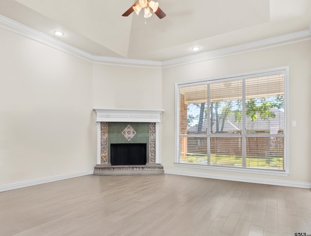 unfurnished living room featuring light hardwood / wood-style floors, ceiling fan, ornamental molding, and a tiled fireplace