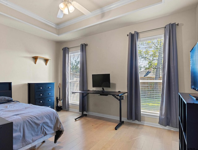 bedroom with a tray ceiling, ceiling fan, crown molding, and light hardwood / wood-style floors