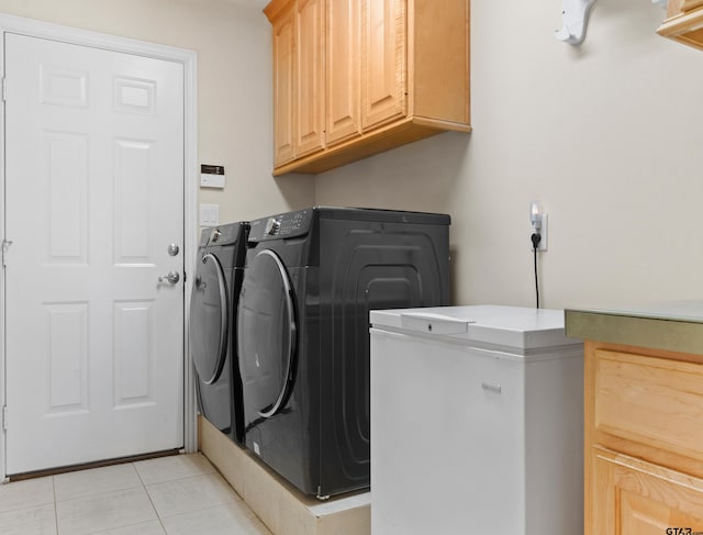 laundry area featuring washer and dryer, light tile patterned flooring, and cabinets