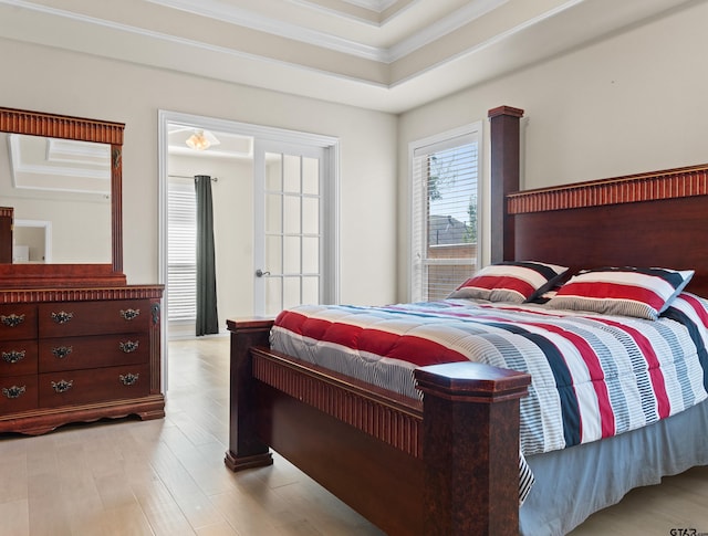 bedroom featuring light hardwood / wood-style floors, ornamental molding, and a tray ceiling