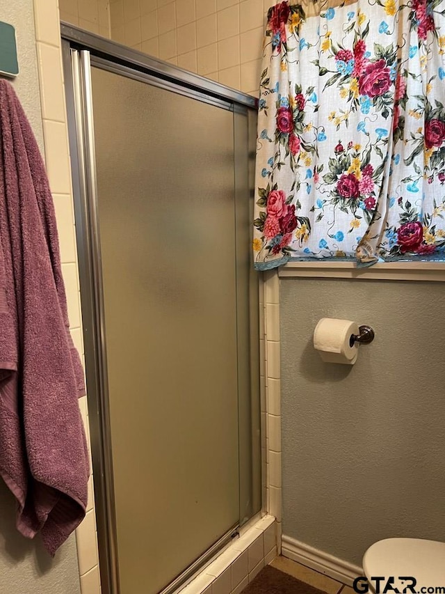 bathroom with an enclosed shower and toilet