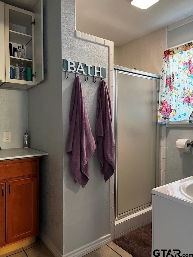 bathroom with vanity, a shower with shower door, and tile patterned floors