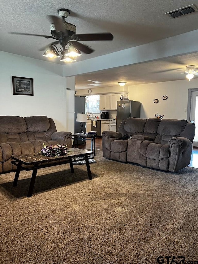 carpeted living room featuring a textured ceiling and ceiling fan