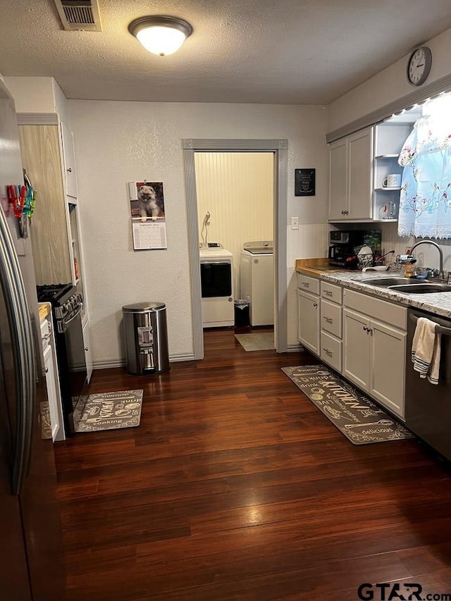 kitchen with appliances with stainless steel finishes, sink, white cabinets, dark wood-type flooring, and washing machine and dryer