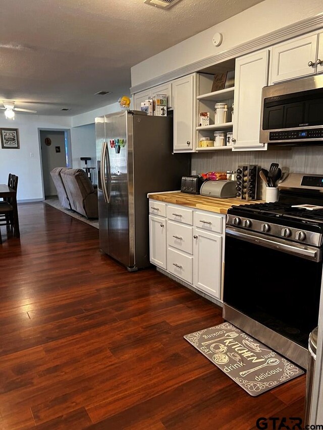 kitchen featuring dark hardwood / wood-style flooring, ceiling fan, wood counters, white cabinetry, and appliances with stainless steel finishes