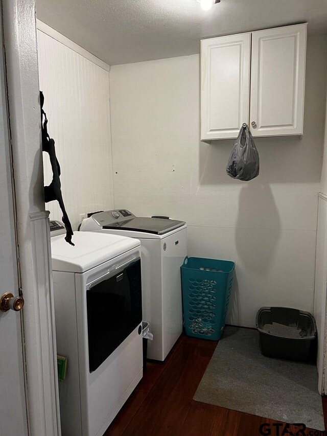 laundry room with dark wood-type flooring, cabinets, a textured ceiling, and washer and clothes dryer