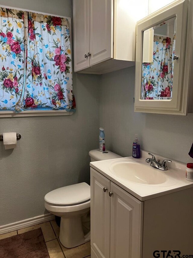 bathroom with tile patterned flooring, vanity, and toilet