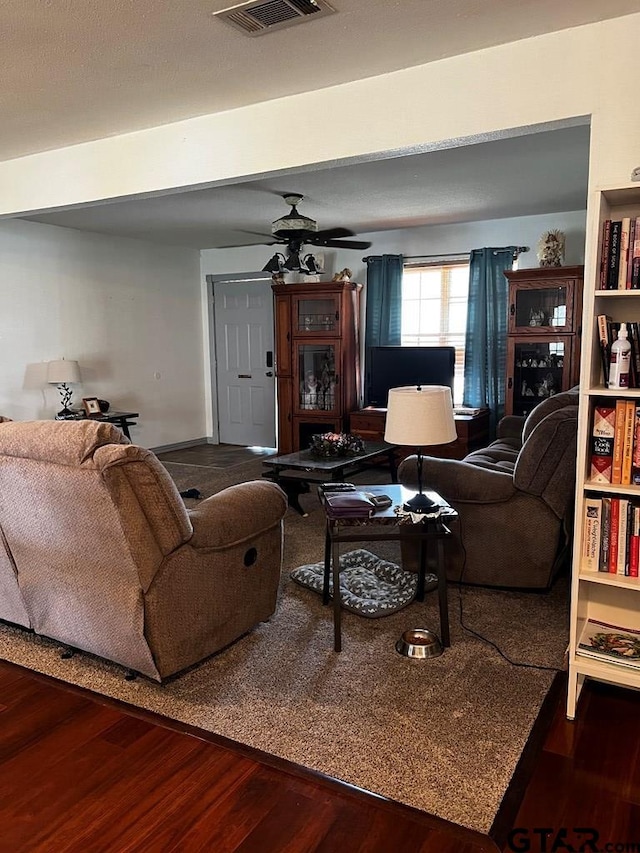 living room with dark hardwood / wood-style flooring and ceiling fan