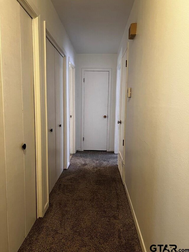 hall featuring dark colored carpet