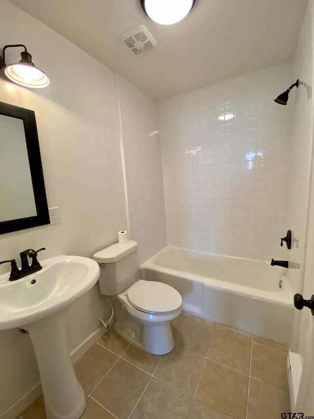 bathroom featuring tile patterned flooring, toilet, and tiled shower / bath