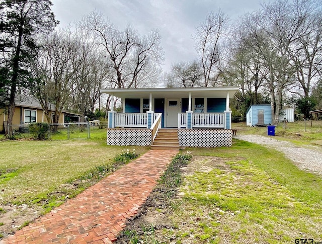 view of front facade featuring a front yard, covered porch, and a shed