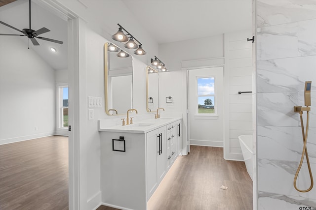 bathroom featuring wood-type flooring, a tub, vaulted ceiling, vanity, and ceiling fan