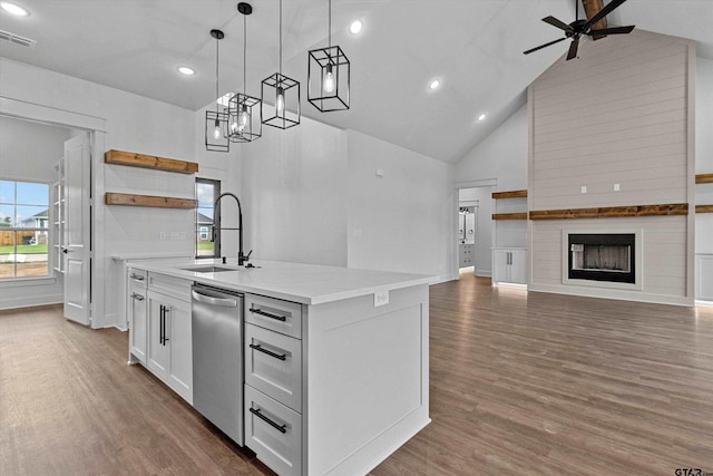 kitchen with sink, high vaulted ceiling, stainless steel dishwasher, a kitchen island with sink, and white cabinets