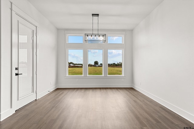 unfurnished dining area with dark wood-type flooring and a chandelier