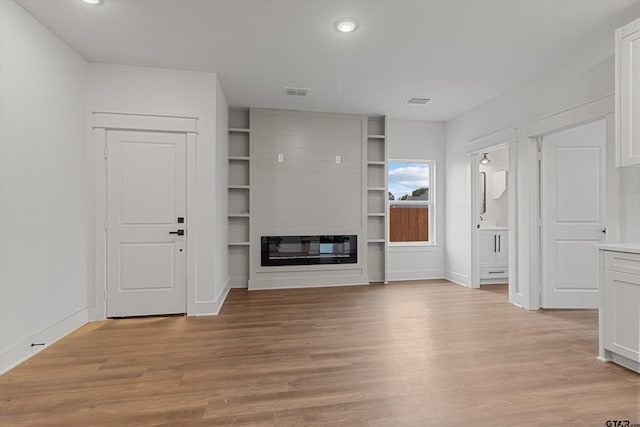 unfurnished living room featuring a large fireplace and light hardwood / wood-style flooring