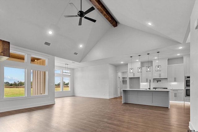 unfurnished living room featuring dark wood-type flooring, beam ceiling, sink, and high vaulted ceiling