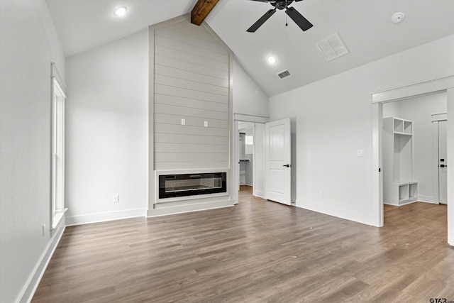 unfurnished living room with hardwood / wood-style floors, a fireplace, beam ceiling, and ceiling fan