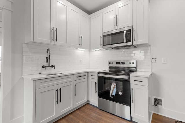 kitchen featuring tasteful backsplash, stainless steel appliances, sink, white cabinets, and dark wood-type flooring