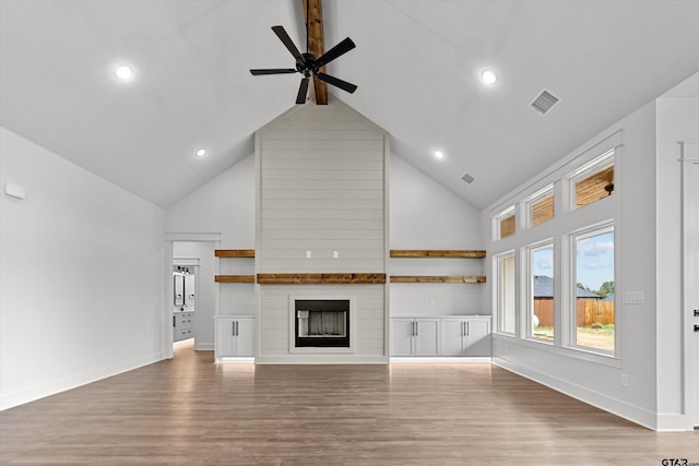 unfurnished living room with hardwood / wood-style flooring, ceiling fan, a large fireplace, and high vaulted ceiling