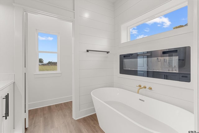 bathroom featuring a wealth of natural light, wood-type flooring, vanity, and a bathing tub