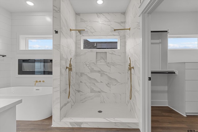 bathroom with hardwood / wood-style flooring, vanity, and plus walk in shower