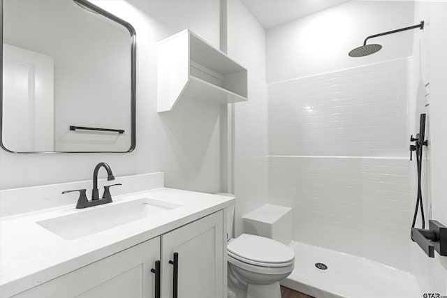 bathroom featuring toilet, vanity, and tiled shower